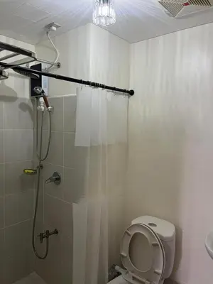 a bathroom with a shower with a toilet and a sink at The Journeyman Suite at Covent Garden Sta Mesa Manila in Manila