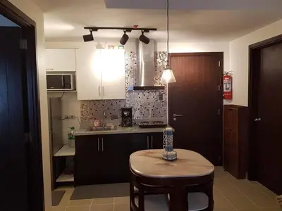 a kitchen with a table and a small table with a bottle on it at The Journeyman Suite at Covent Garden Sta Mesa Manila in Manila
