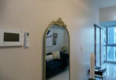 a mirror in a room with a couch and a tv at Uptown BGC Taguig - One Bedroom in Manila