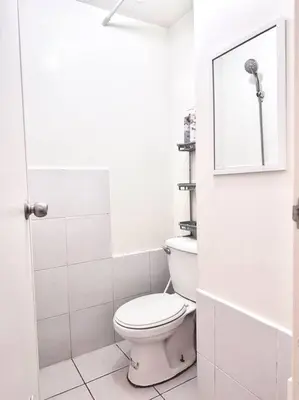a white bathroom with a toilet and a mirror at Arkisha’s Cozy Place in Manila