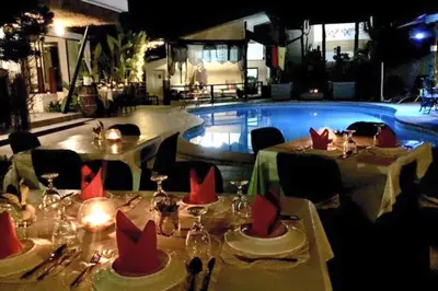 a table with red napkins on it next to a pool at Date & Dine Resort in Antipolo