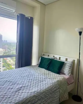 a bedroom with a bed with a blue curtain and a window at Makati Penthouse with Stunning City Skyline View in Manila