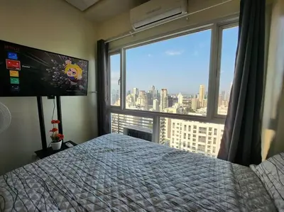 a bedroom with a bed and a large window at Makati Penthouse with Stunning City Skyline View in Manila