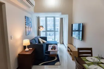 a living room with a blue couch and a table at A2J Luxury Uptown 3BR Suite Near Uptown Mall in Manila