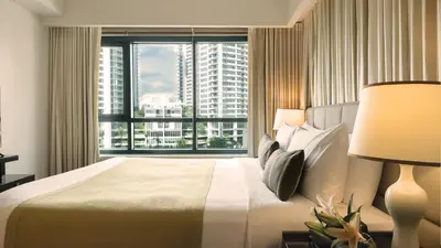 a bedroom with a large bed and a large window at Aruga Apartments by Rockwell Makati in Manila