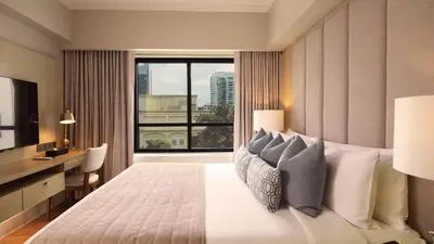 a bedroom with a large bed with a large window at Aruga Apartments by Rockwell Makati in Manila