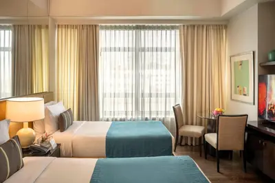 a hotel room with two beds and a desk at Aruga Apartments by Rockwell Makati in Manila