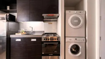 a kitchen with a stove and a washing machine at Aruga Apartments by Rockwell Makati in Manila