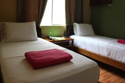 a hotel room with two beds with a red pillow on it at Purple Tree Bed & Breakfast in Manila