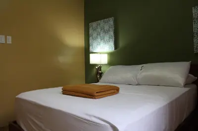 a white bed with a brown towel on it at Purple Tree Bed & Breakfast in Manila