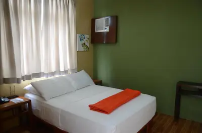 a bedroom with a white bed with an orange towel on it at Purple Tree Bed & Breakfast in Manila