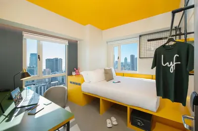 a room with a bed with a shirt hanging on the wall at lyf Malate Manila managed by The Ascott Limited in Manila