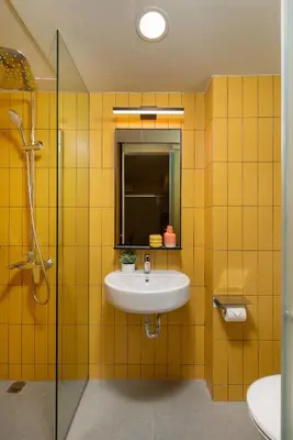 a yellow tiled bathroom with a sink and a shower at lyf Malate Manila managed by The Ascott Limited in Manila