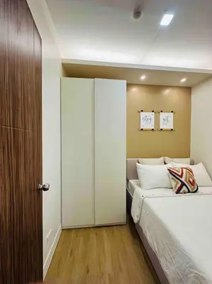 a bedroom with a white bed and a closet at Jeced Condotel at Spring Residences near Airport in Manila