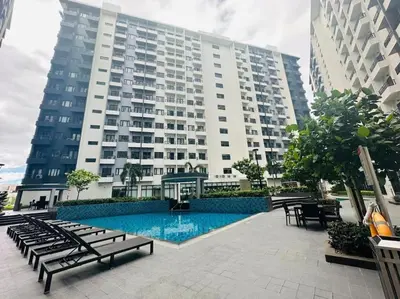 a large building with a swimming pool in front of a building at Jeced Condotel at Spring Residences near Airport in Manila