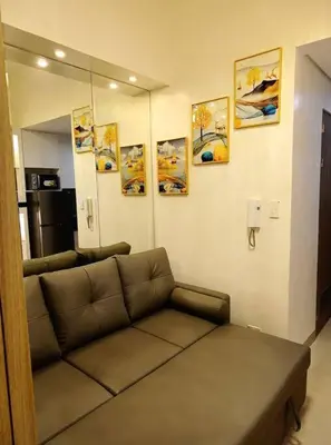 a couch in a living room with paintings on the wall at Skyia's Pod a Premier Suite at Shore 2 Residences in Manila