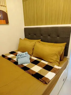 a bed with a checkered blanket and yellow pillows at Skyia's Pod a Premier Suite at Shore 2 Residences in Manila