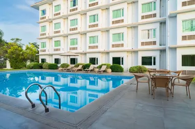 a hotel swimming pool with chairs and a table next to a building at Microtel by Wyndham South Forbes near Nuvali in Santa Rosa