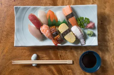 a plate of sushi and vegetables on a table with chopsticks at Microtel by Wyndham South Forbes near Nuvali in Santa Rosa