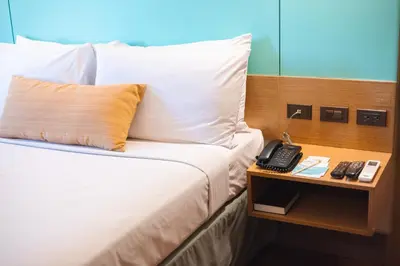 a bed in a hotel room with a phone on a night stand at Microtel by Wyndham South Forbes near Nuvali in Santa Rosa