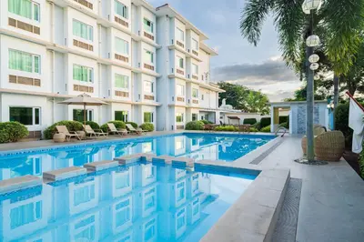 a swimming pool in front of a building at Microtel by Wyndham South Forbes near Nuvali in Santa Rosa