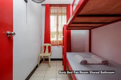 a small bedroom with a bunk bed and a chair at Stay Malate (Wanderers Guest House) in Manila