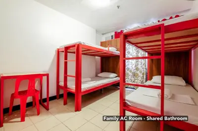 two red bunk beds in a room with a chair at Stay Malate (Wanderers Guest House) in Manila