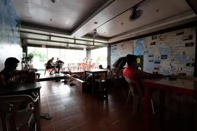 a group of people sitting at tables in a restaurant at Stay Malate (Wanderers Guest House) in Manila