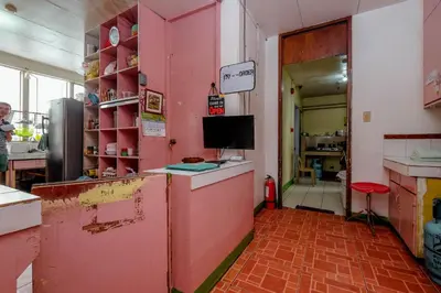 a kitchen with a pink wall with a counter in it at Stay Malate (Wanderers Guest House) in Manila