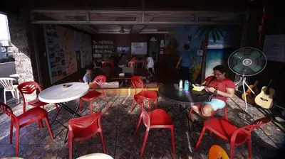 a woman sitting at a table in a room with red chairs at Stay Malate (Wanderers Guest House) in Manila