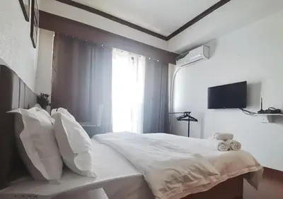 a white bed with white pillows and a window at passion makati in Manila