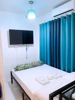 a room with a bed with blue curtains and a flat screen tv at Blue Diamond Staycation beside Enchanted Kingdom in Santa Rosa Laguna in Santa Rosa