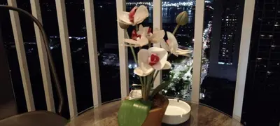 a vase with flowers on a table in front of a window at The SPARKLE Comfortable living by Awsom Phil in Manila