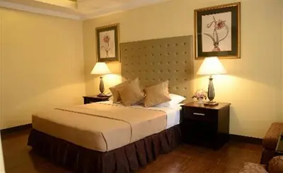 a bedroom with a bed with two lamps and two tables at Silver Oaks Suites & Hotel in Manila