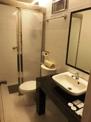 a bathroom with a sink and a toilet and a mirror at Silver Oaks Suites & Hotel in Manila