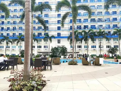 a hotel with palm trees in front of a building at Sea Residences 5mins walk to SM MoA, Arena, SMX, 55