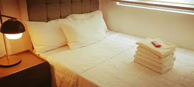 a white bed with a lamp and a stack of pillows at The ICONIC: Comfortable living by Awsom Phil in Manila