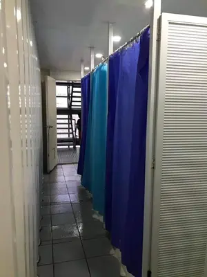 a row of blue shower stalls in a hallway at Burgos Hub Hostel in Manila
