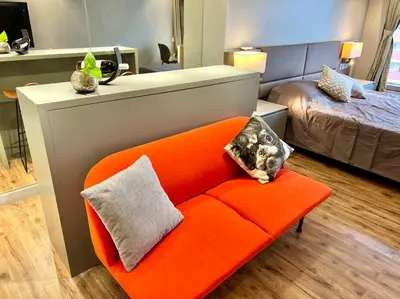 an orange couch in a room with a bed at Luxury Studio in heart of Ortigas w/ swimming pool in Manila
