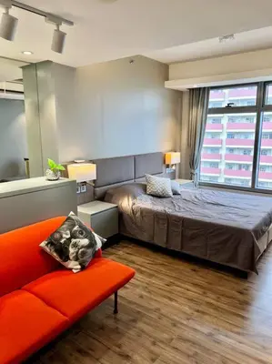 a bedroom with a bed and a couch and a window at Luxury Studio in heart of Ortigas w/ swimming pool in Manila