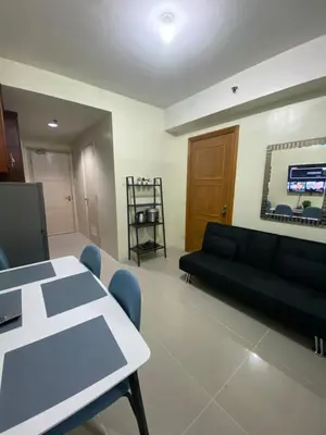 a living room with a black couch and a table at Sea Residences MOA by Ruffa's Condotel in Manila