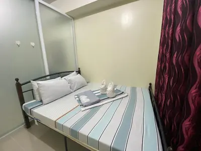 a small bed with a tray with a book on it at Sea Residences MOA by Ruffa's Condotel in Manila