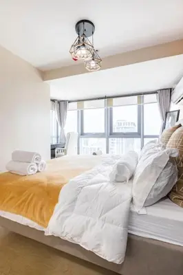 a white bedroom with a large bed with a chandelier at Luxury living @ Eastwood in Manila