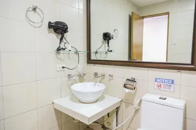 a bathroom with a sink and a mirror and a toilet at Pacific Bay Grand Suites in Manila