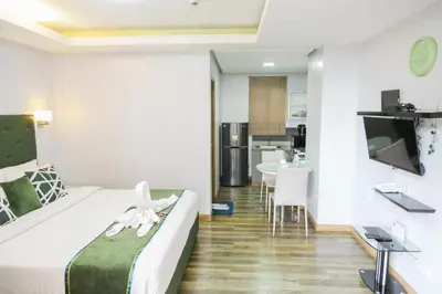a bedroom with a bed and a dining room at Pacific Bay Grand Suites in Manila