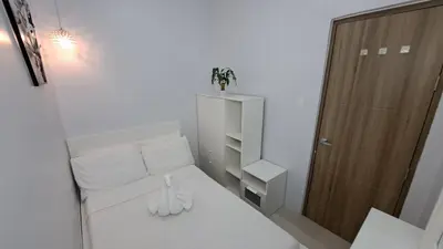 a small room with a white bed and a wooden door at Stunning 1-Bedroom Condo in Manila