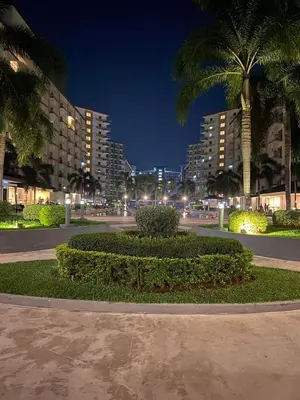 a park with palm trees and buildings at night at Stunning 1-Bedroom Condo in Manila