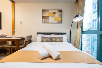 a bedroom with a bed with a desk and a table at One Uptown Residence 1Br 2Bed Affordable for 4,Uptown Mall Linked in Manila