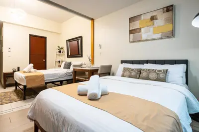 a hotel room with two beds and a desk at One Uptown Residence 1Br 2Bed Affordable for 4,Uptown Mall Linked in Manila
