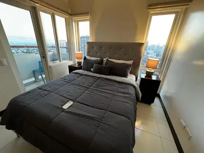 a bedroom with a large bed with large windows at AMAZING VIEWS ACROSS SHANGRILA MALL and NEAR MEGAMALL GREENFIELD DISTRICT in Manila